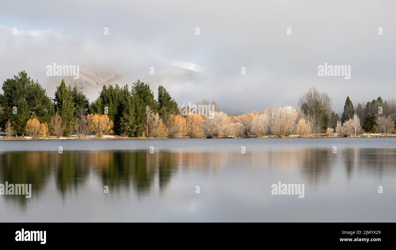 Fog lifting above Wairepo Arm of Lake Ruatuniwha, melting hoar frost reflected in the lake, Twizel, Canterbury. Stock Photo