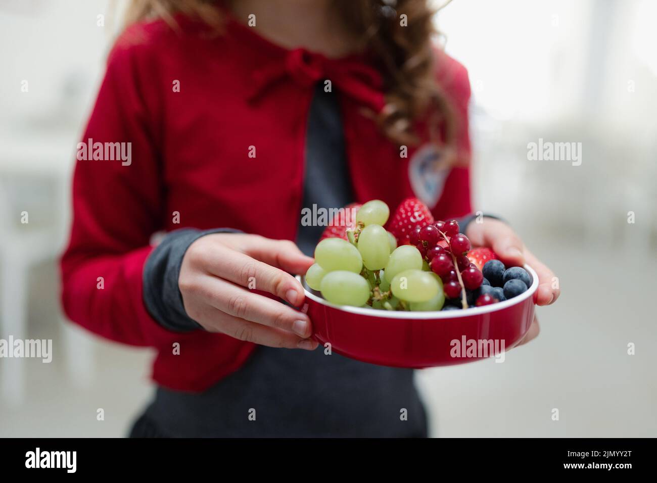 Closse-up of schoolchild having healthy fruit lunch in school canteen. Stock Photo
