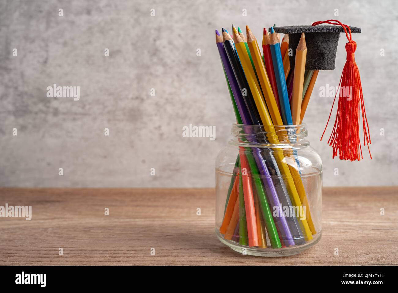 Graduation hat with colorful pencils on book with copy space, learning