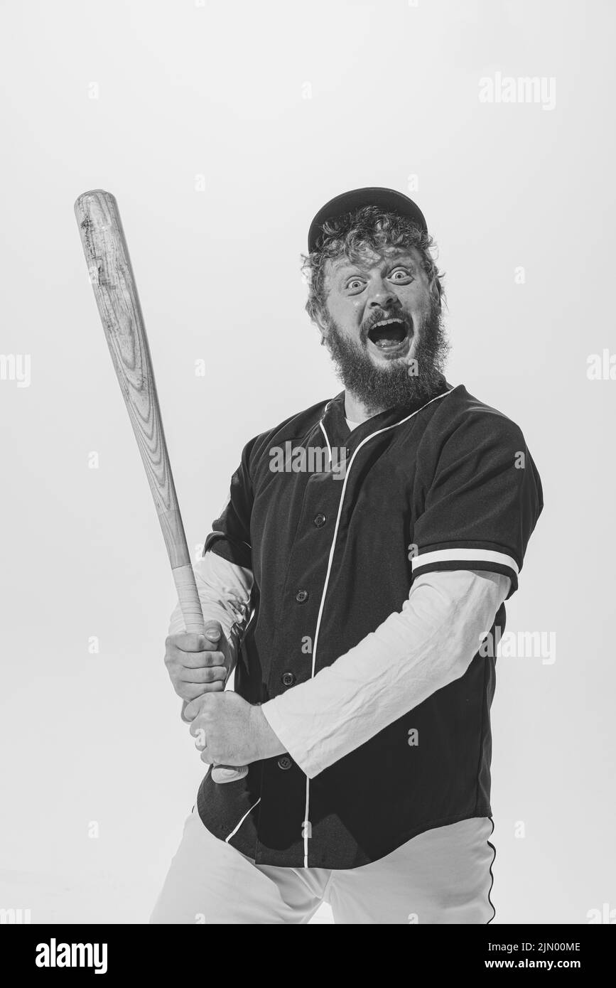 Excited male baseball player wearing retro sports uniform and holding bat isolated on white background. Vintage baseball batter Stock Photo