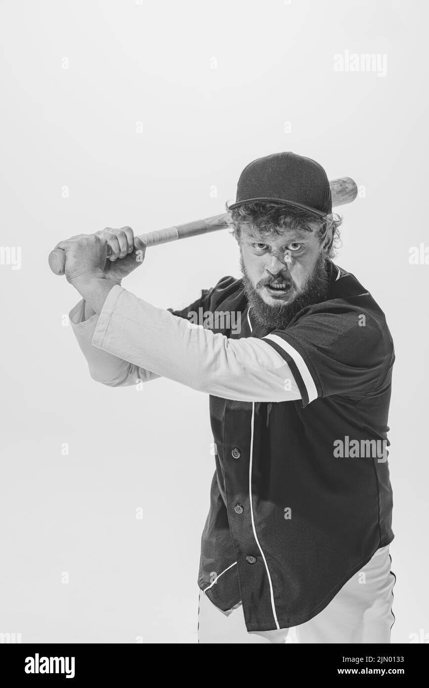 Fighting spirit. Emotional male baseball player wearing retro sports uniform and holding bat isolated on white background. Vintage baseball batter Stock Photo