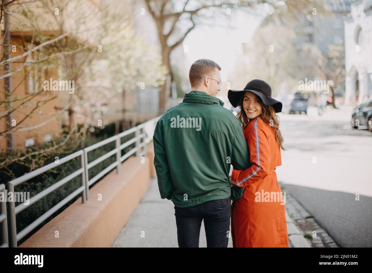Rear view of young couple in love walking outdoors at the city street ...