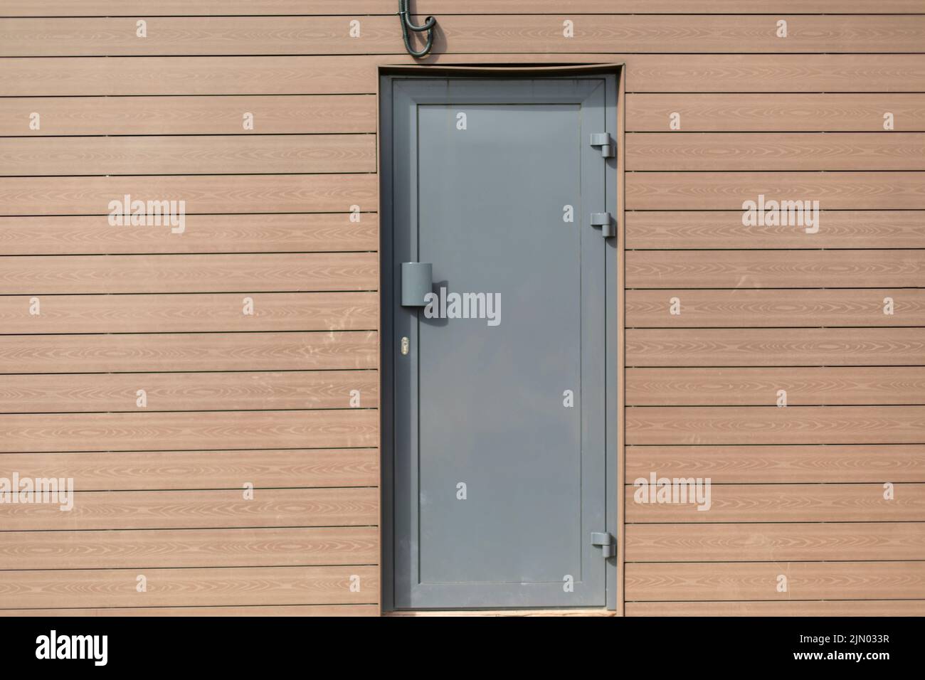 Technical entrance to building. Grey door. Narrow door in wall Stock