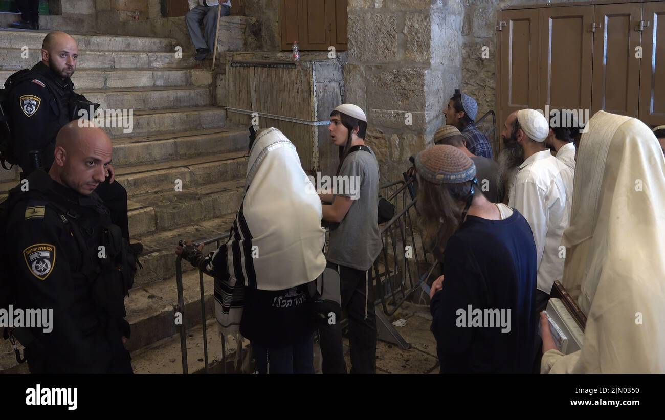 Israeli policemen stand guard as religious Jews pray at Bab al-Qattanin Gate, which leads to the Temple Mount in the Muslim Quarter, on the Jewish feast of Tisha B'Av on August 7, 2022 in Jerusalem, Israel. Jewish people around the world read from the Book of Lamentations, marking the beginning of Tisha B'Av, the annual fasting day commemorating the destruction of the First and Second Temples in Jerusalem Stock Photo