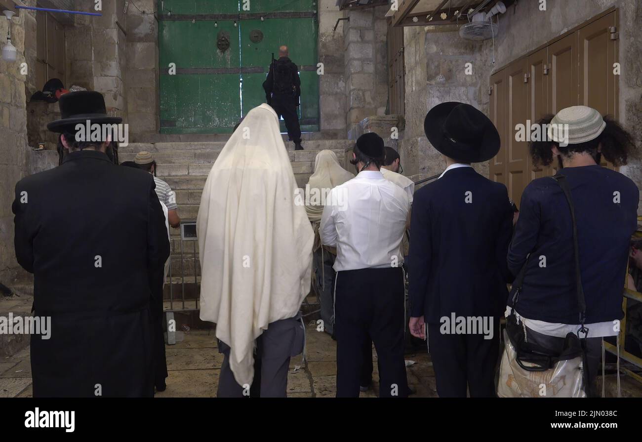 Religious Jews pray as they mourn at Bab al-Qattanin Gate, which leads to the Temple Mount in the Muslim Quarter, on the Jewish feast of Tisha B'Av on August 7, 2022 in Jerusalem, Israel. Jewish people around the world read from the Book of Lamentations, marking the beginning of Tisha B'Av, the annual fasting day commemorating the destruction of the First and Second Temples in Jerusalem Stock Photo