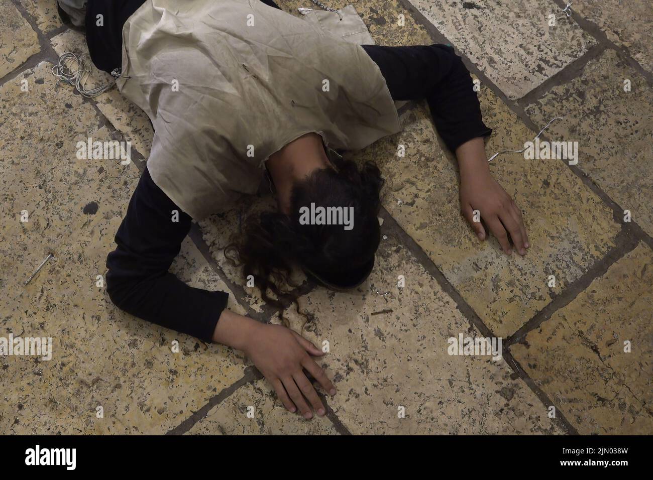 A religious Jew prostrates on the ground in prayer as Jews mourn at Bab al-Qattanin Gate, which leads to the Temple Mount in the Muslim Quarter, on the Jewish feast of Tisha B'Av on August 7, 2022 in Jerusalem, Israel. Jewish people around the world read from the Book of Lamentations, marking the beginning of Tisha B'Av, the annual fasting day commemorating the destruction of the First and Second Temples in Jerusalem Stock Photo