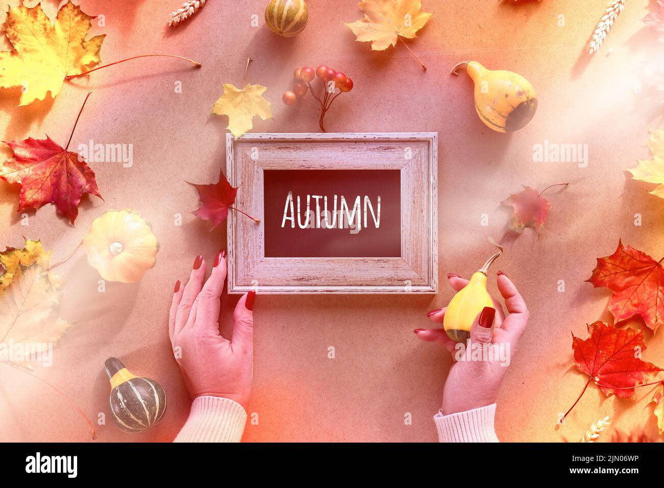 Autumn frame, caption greeting text Autumn. Hands with frame and