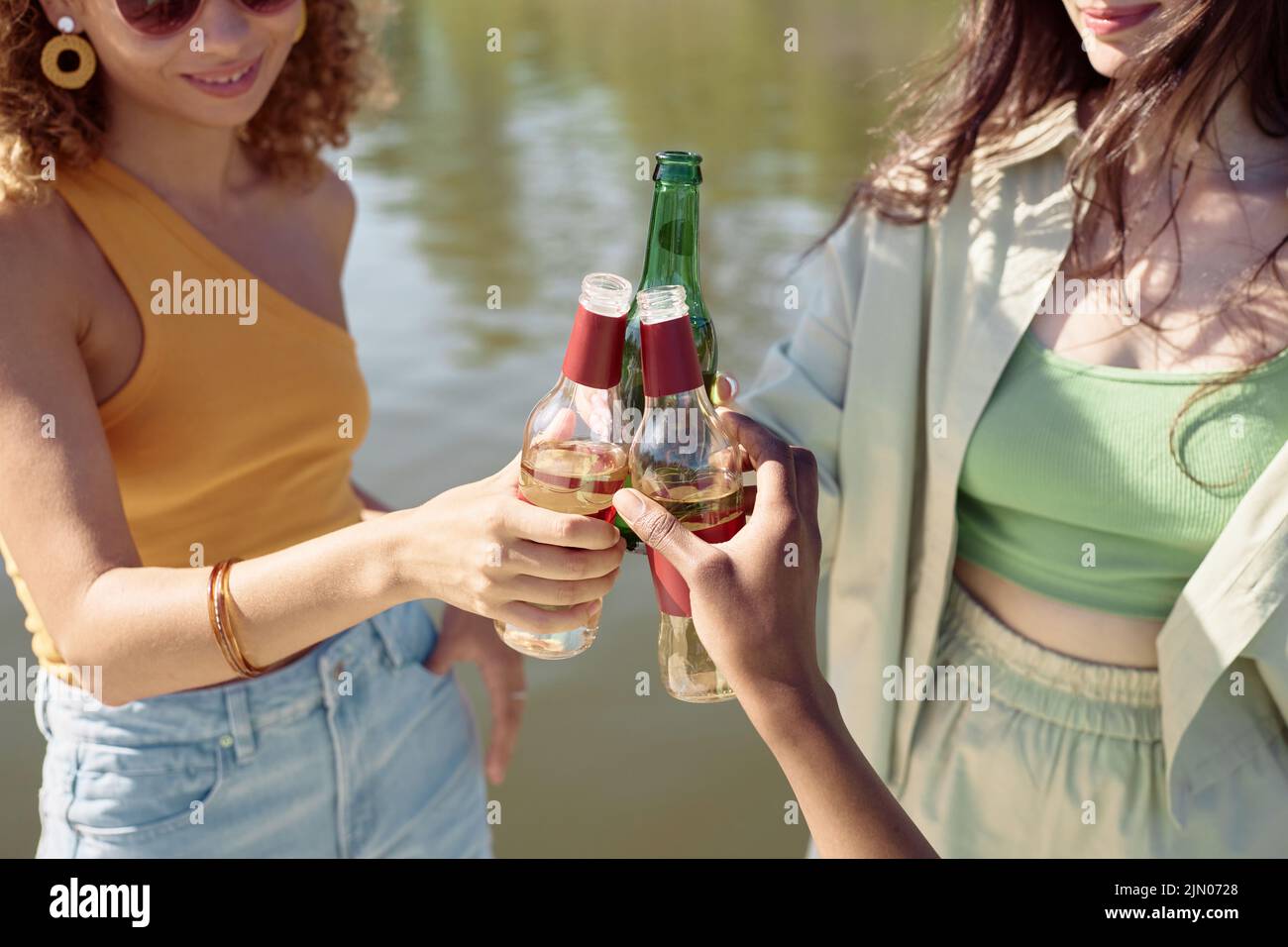 Close up of three young girls clinking bottles while enjoying Summer vacation Stock Photo