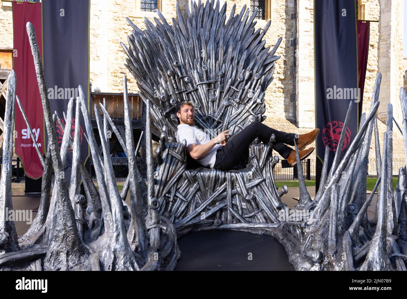 EDITORIAL USE ONLY Reality TV star Sam Thompson sits on the Iron Throne outside the Tower of London to mark the launch of the Game of Thrones prequel, House of the Dragon, airing on Sky and streaming service NOW from August 22. PA PHOTO Picture date: Monday August 8, 2022.. The throne is being displayed at the Tower of London today and tomorrow, ahead of the House of the Dragon premiere next week in Leicester Square. Fans and Visitors to the Tower of London will be able to discover more about the news series via a QR code next to the Iron Throne. The Throne will then be touring the country, in Stock Photo