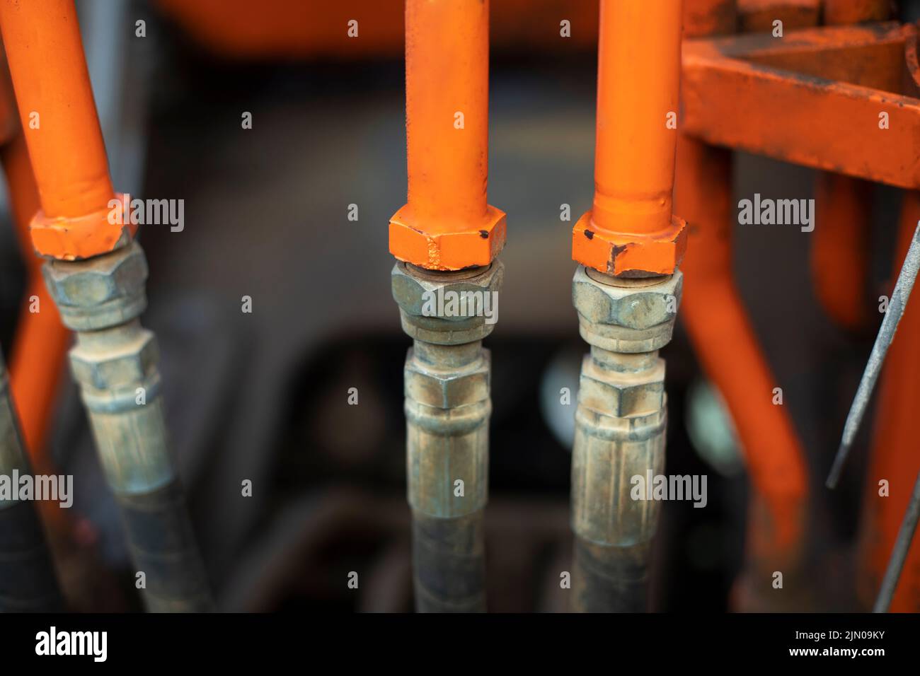 Steel fuel pipes. Tractor parts. Heavy machinery up close. Orange