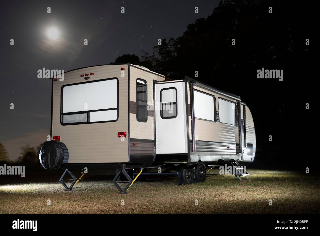 Travel trailer with slides out and moon and stars above Stock Photo