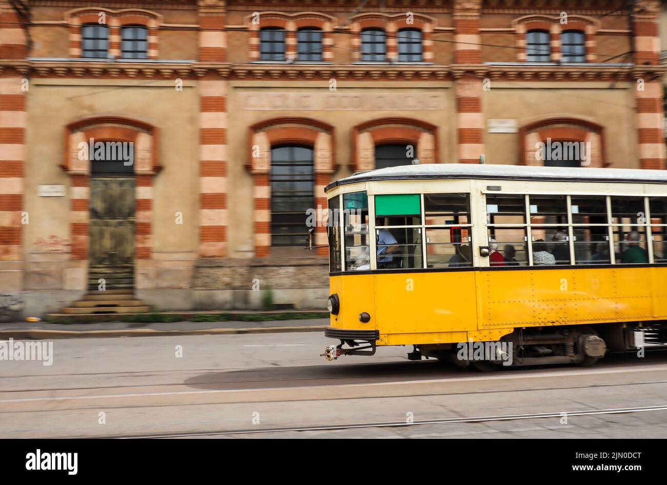 Panning Shot of Yellow Tram in Milan. Colorful Electric Streetcar in Italy. Stock Photo