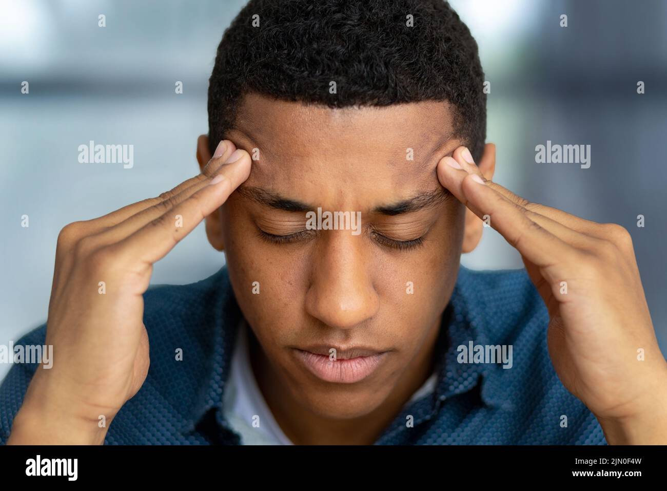 Portrait of tired stressed man having headache feeling sick Male holding his temples suffering from migraine Stock Photo