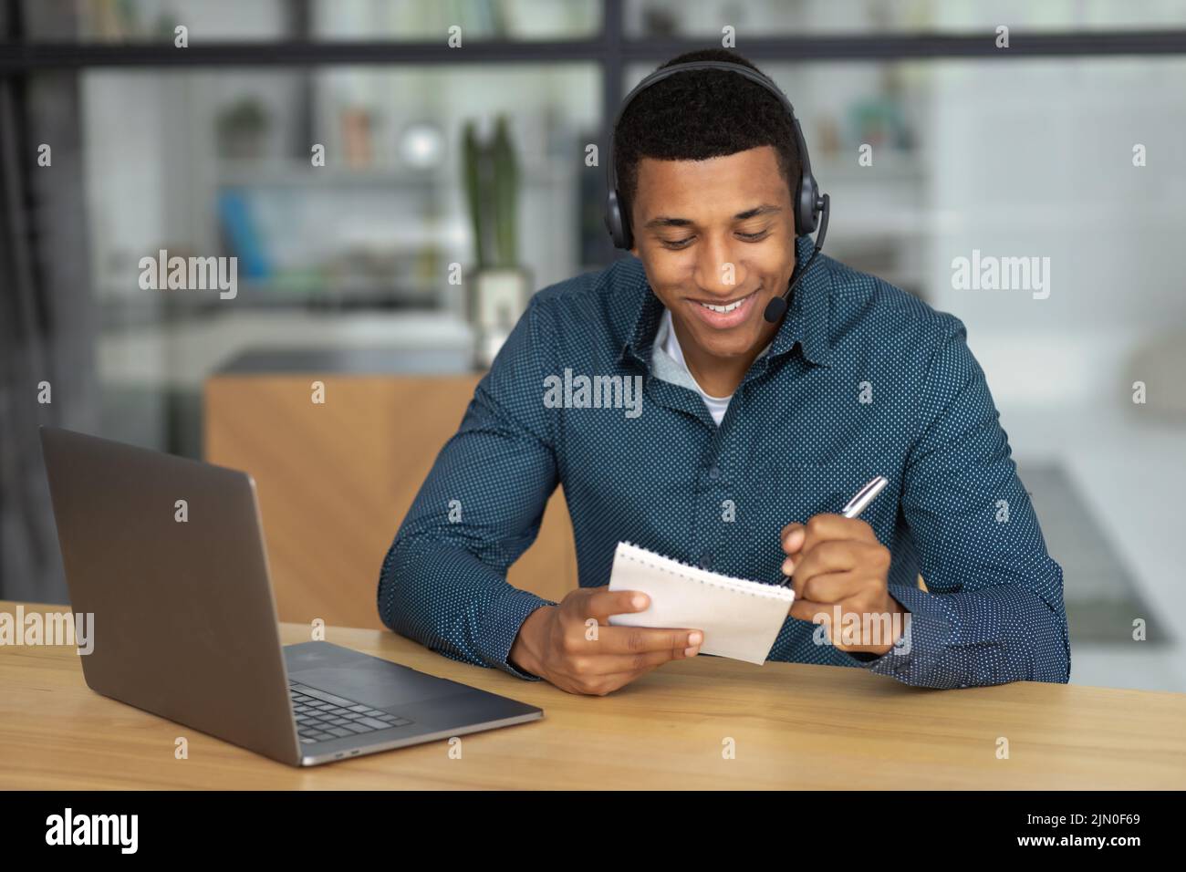 Confident young man Successful student or office worker in headset working using laptop Stock Photo