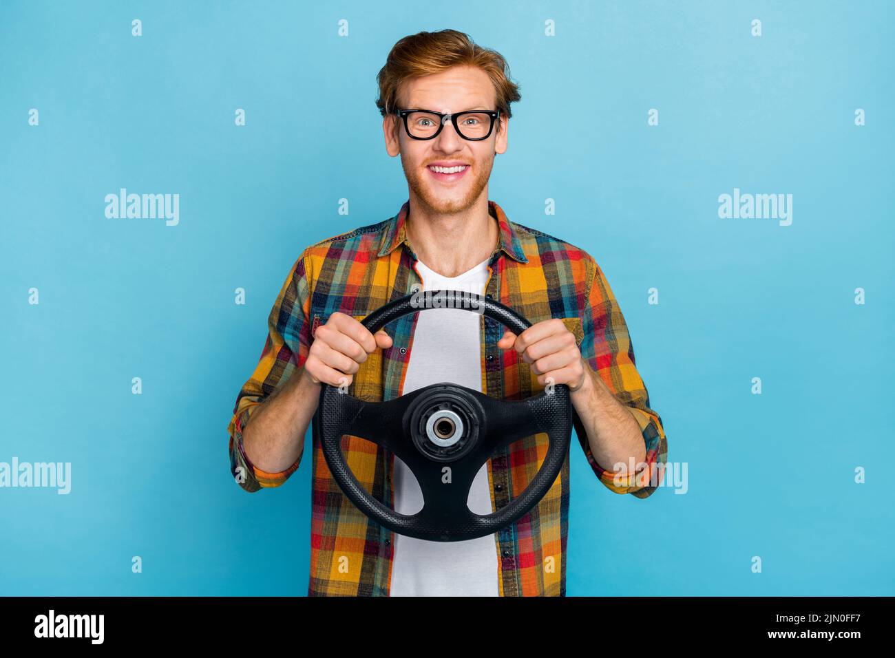 Photo of staring impressed guy with red hairstyle dressed checkered shirt holding steering wheel isolated on blue color background Stock Photo