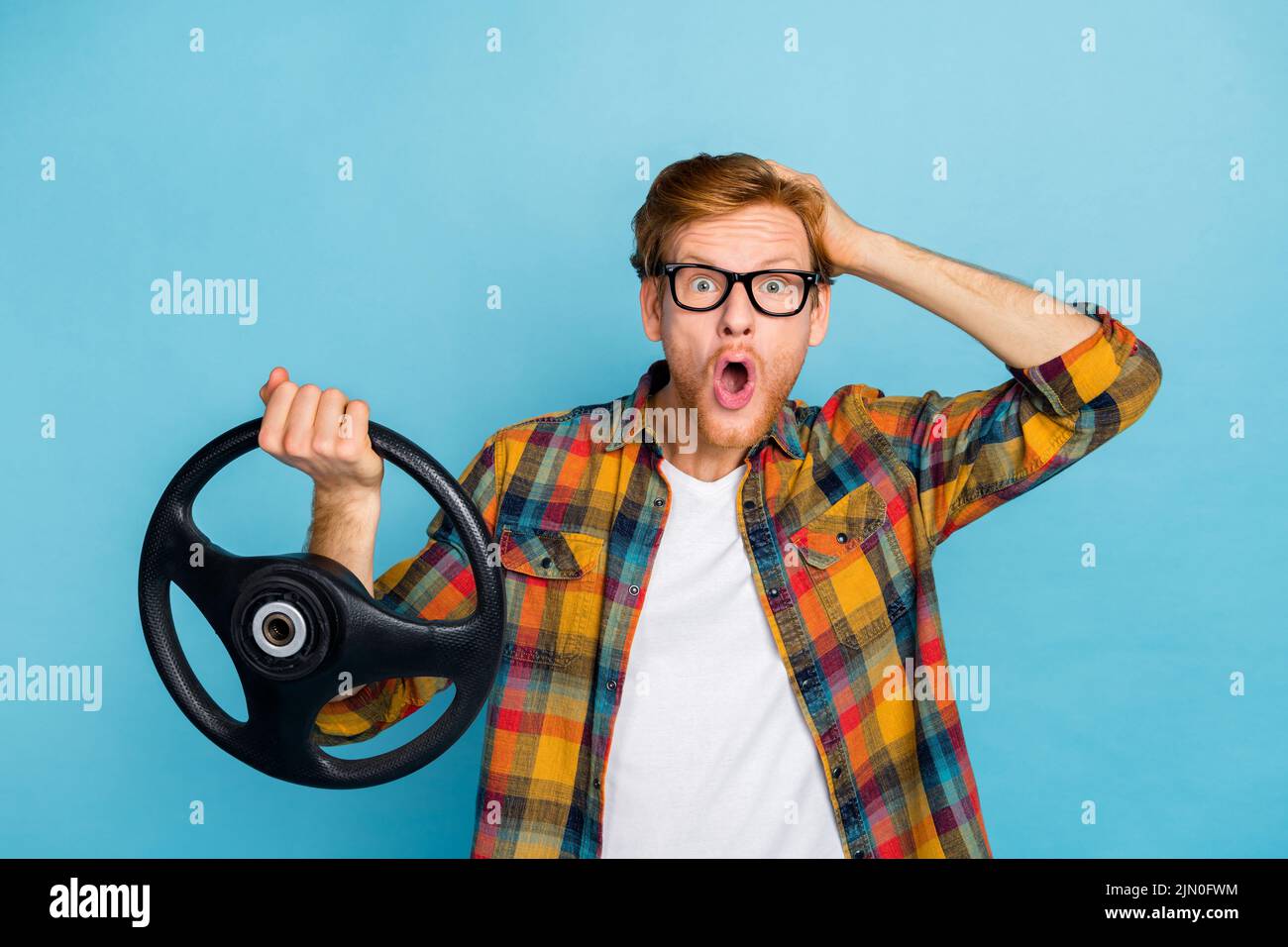 Photo of speechless open mouth guy in glasses with red hairstyle hold steering wheel hand on head isolated on blue color background Stock Photo