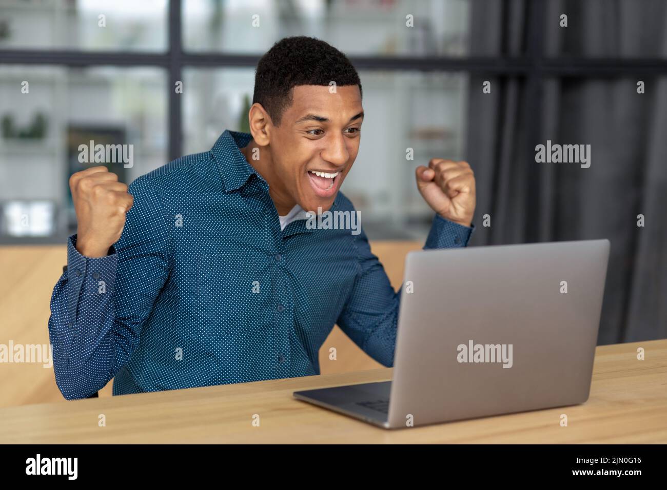 Portrait of excited young African American man celebrating success Happy businessperson male having good news Stock Photo