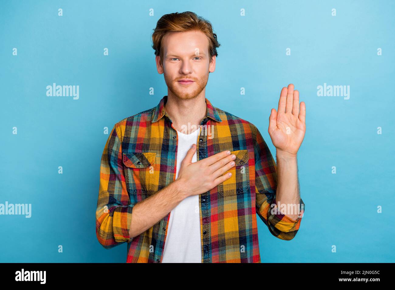 Photo of kind thankful person with ginger hairstyle dressed plaid stylish shirt hold one hand on heart isolated on blue color background Stock Photo