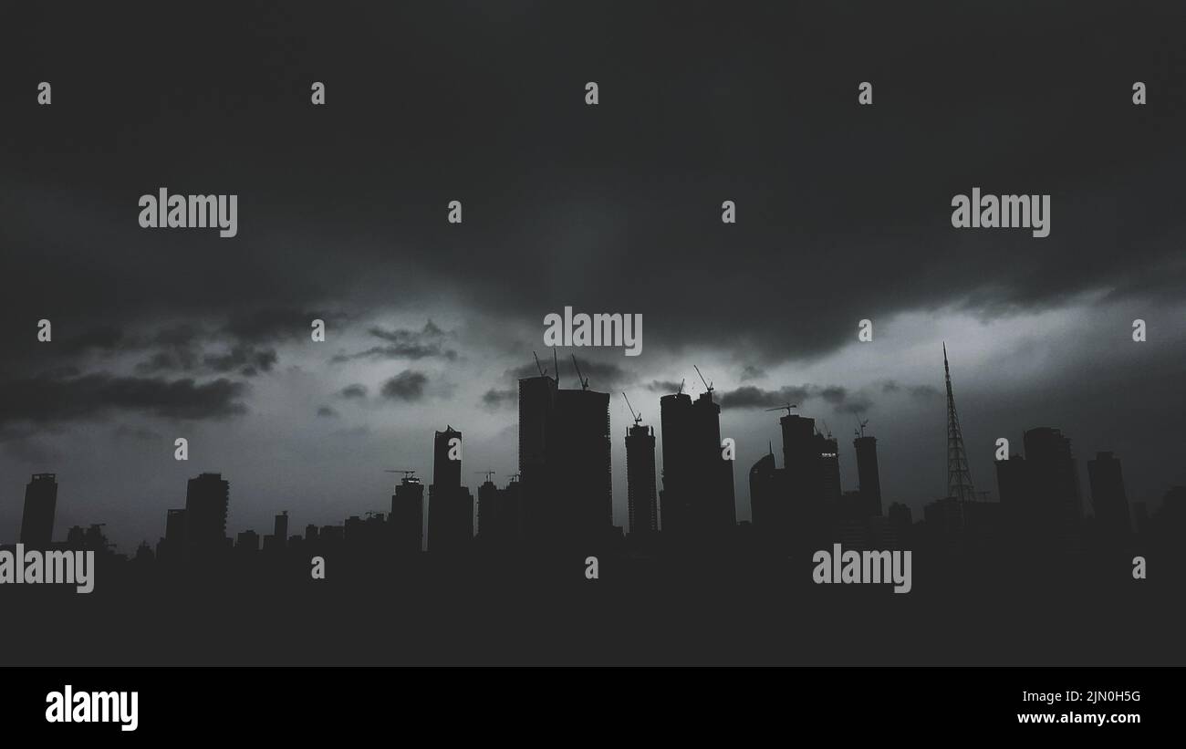 A grayscale shot of silhouettes of the skyscrapers of Mumbai in a mysterious monsoon Stock Photo
