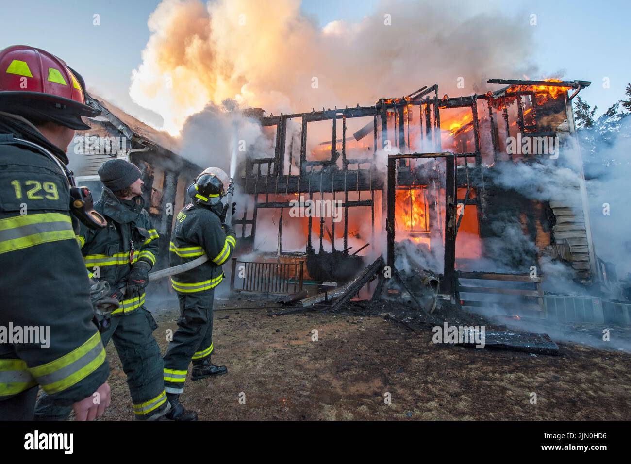 A team of three firefighters works to extinguish the fire as shortly before 6:00 a.m. on Saturday, March 8th, 2014 the Bridgehampton Fire Department w Stock Photo