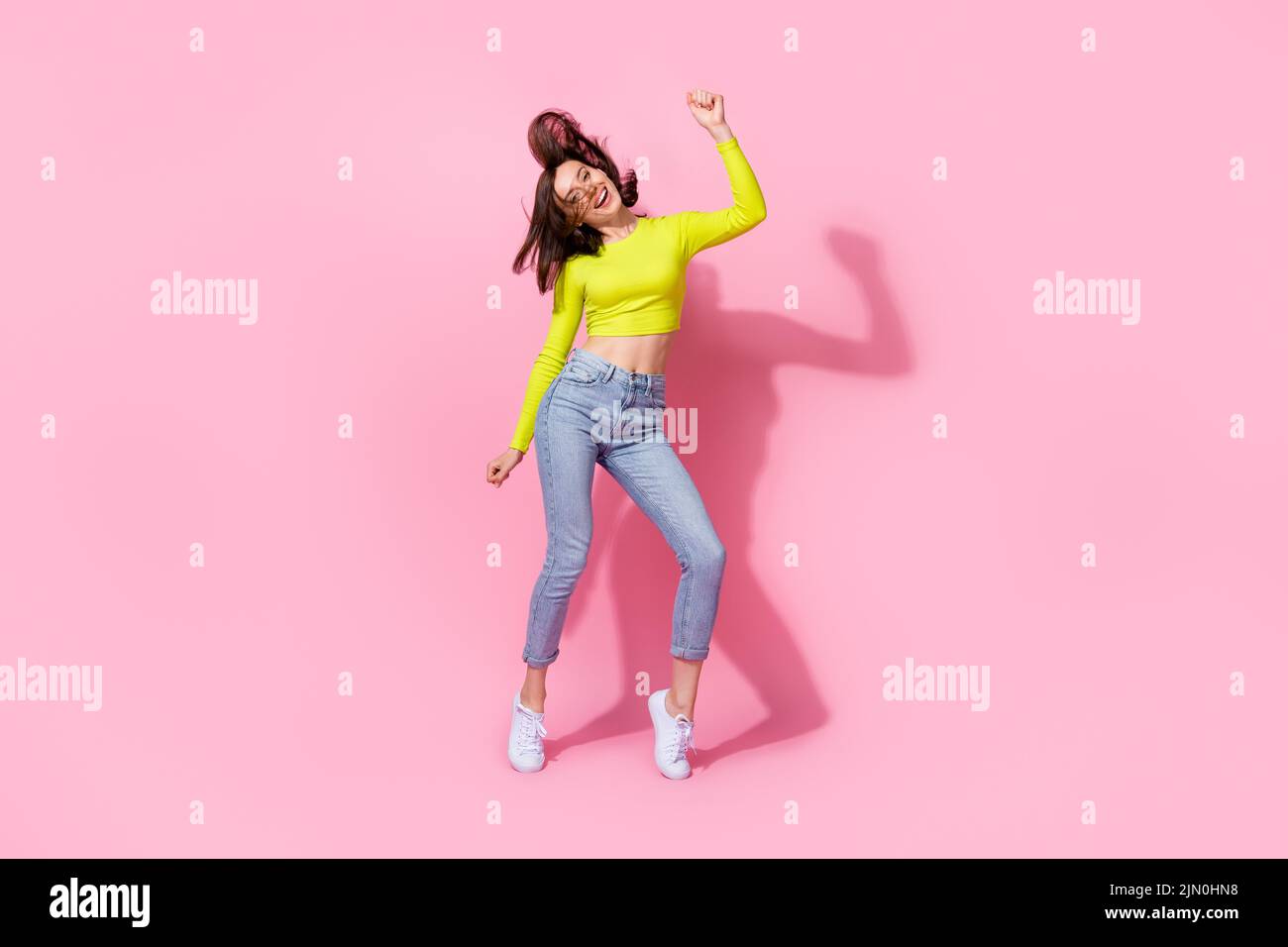 Full body photo of adorable slim sweet girl satisfied new trendy outfit good mood raise arm enjoy dance isolated on pink color background Stock Photo