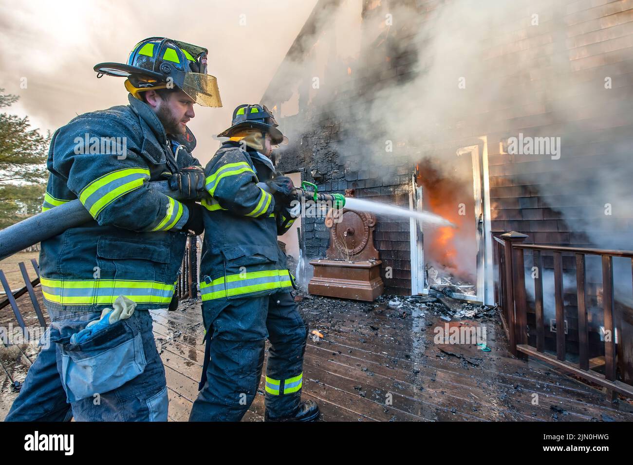A team of two firefighters works to extinguish the fire as shortly before 6:00 a.m. on Saturday, March 8th, 2014 the Bridgehampton Fire Department was Stock Photo