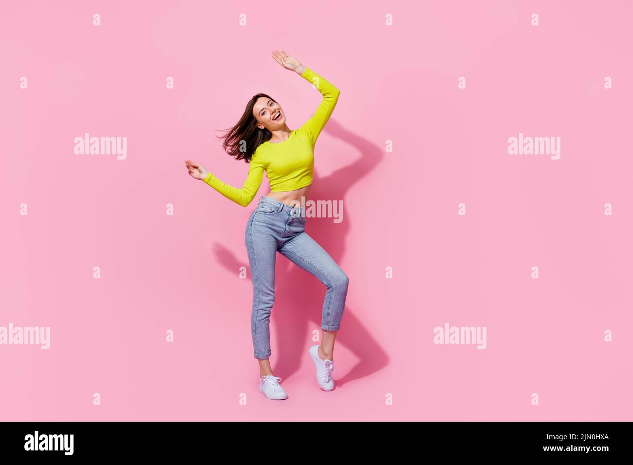 Full body photo of adorable slim sweet sexy girl satisfied party time have fun raise arm enjoy isolated on pink color background Stock Photo