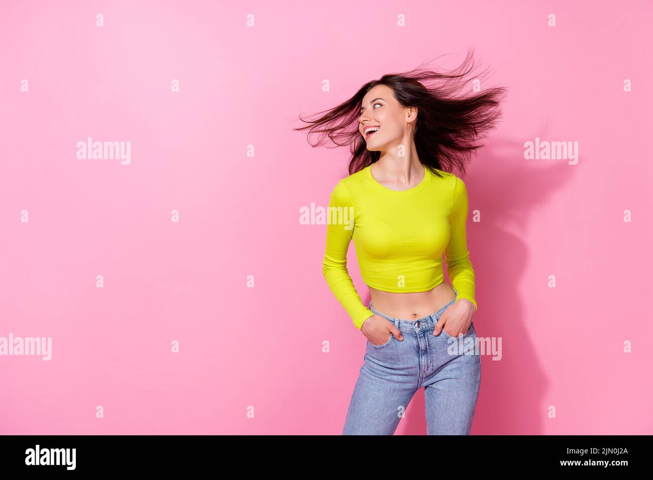 Photo of funky adorable girl dressed lime shirt wind blowing looking empty space isolated pink color background Stock Photo
