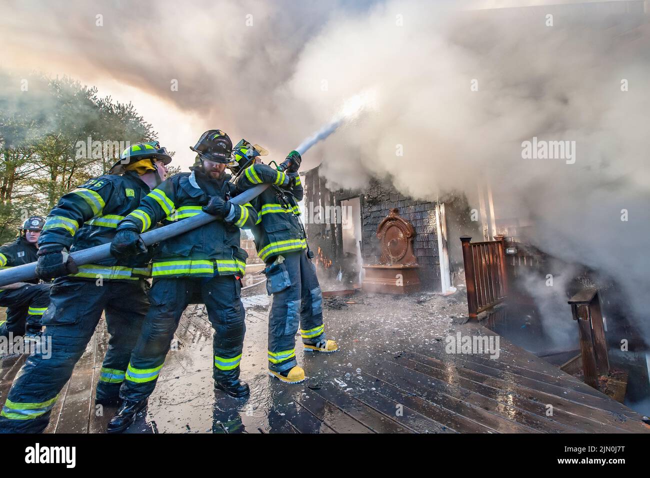 A team of three firefighters works to extinguish the fire as shortly before 6:00 a.m. on Saturday, March 8th, 2014 the Bridgehampton Fire Department w Stock Photo