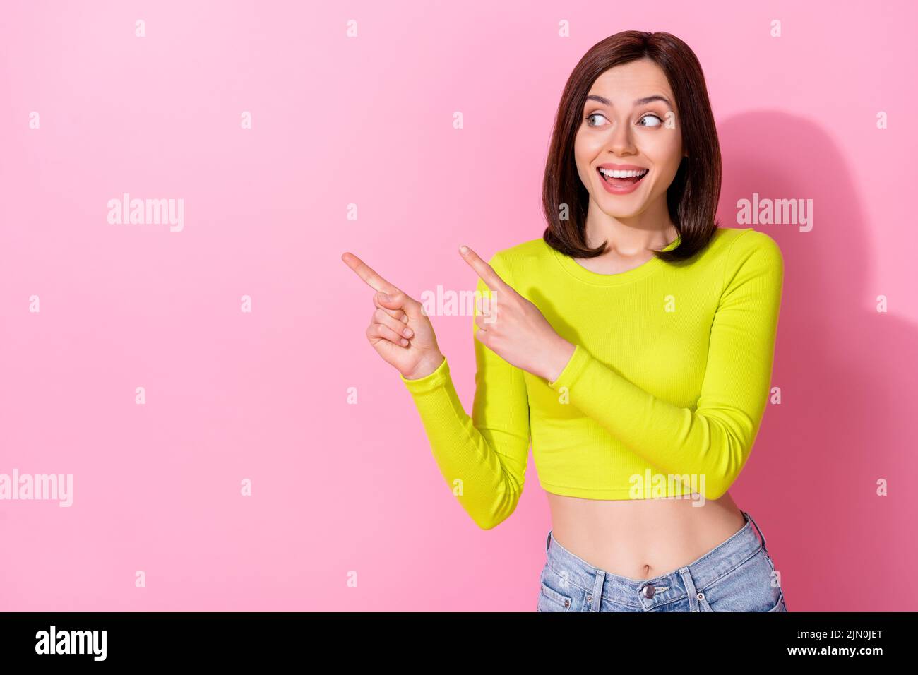 Photo of funny dreamy girl dressed lime shirt looking pointing two fingers empty space isolated pink color background Stock Photo