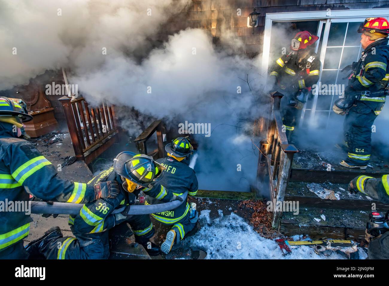 A team of three firefighters works to extinguish fire in the basement of the building as shortly before 6:00 a.m. on Saturday, March 8th, 2014 the Bri Stock Photo