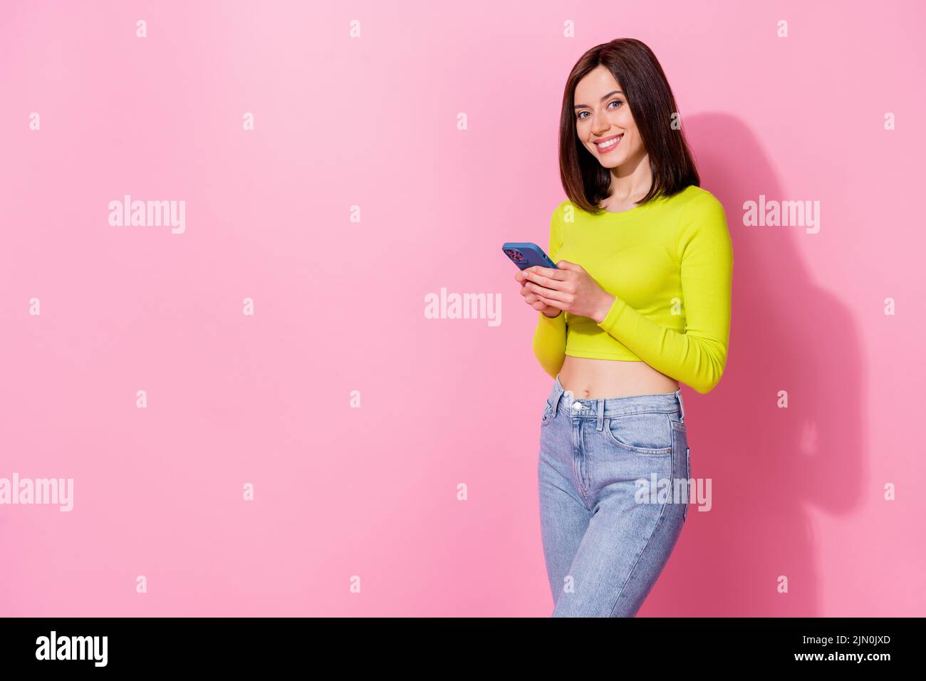 Photo of funky pretty girl dressed lime shirt chatting modern device empty space isolated pink color background Stock Photo