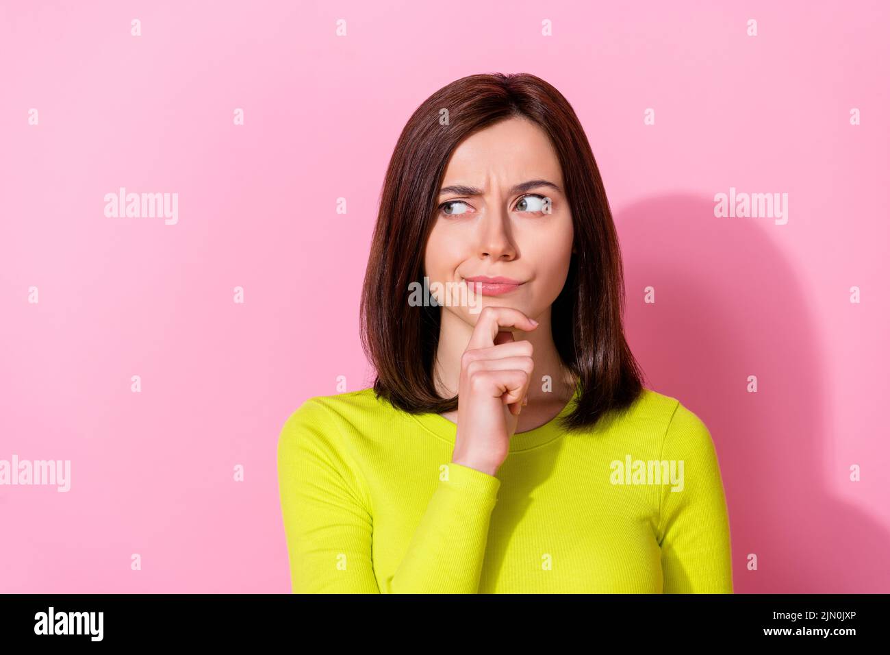 Photo of pretty minded doubtful lady look interested empty space hand touch chin isolated on pink color background Stock Photo