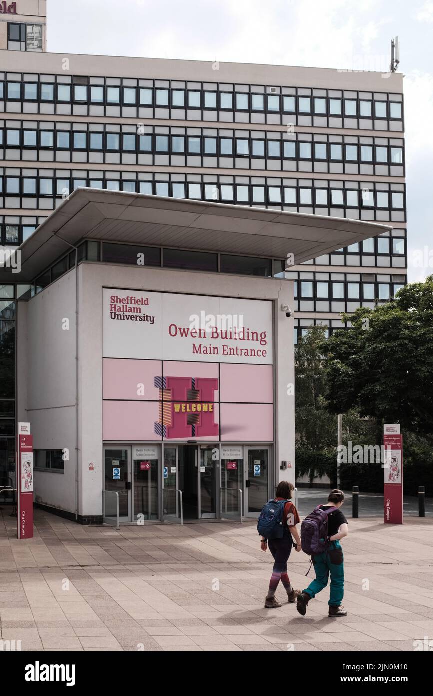 Two people walk past the main entrance of the Owen Building at Sheffield Hallam University on Arundel Gate Stock Photo