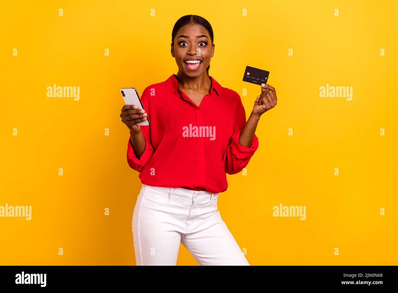 Photo of young excited girl shopping order bank card benefit cashback profit use mobile isolated over yellow color background Stock Photo