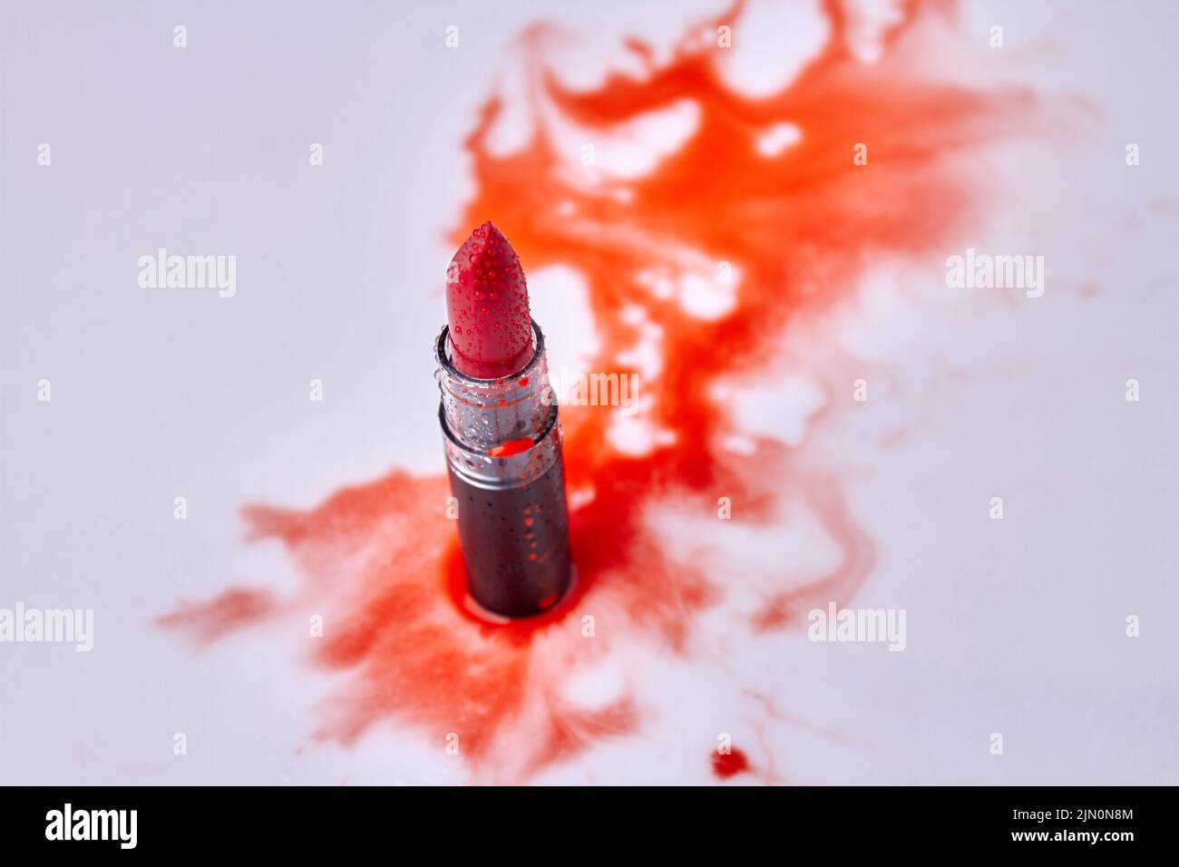 Red lipstick with water droplets top view. Wet red stains on white background. Stock Photo