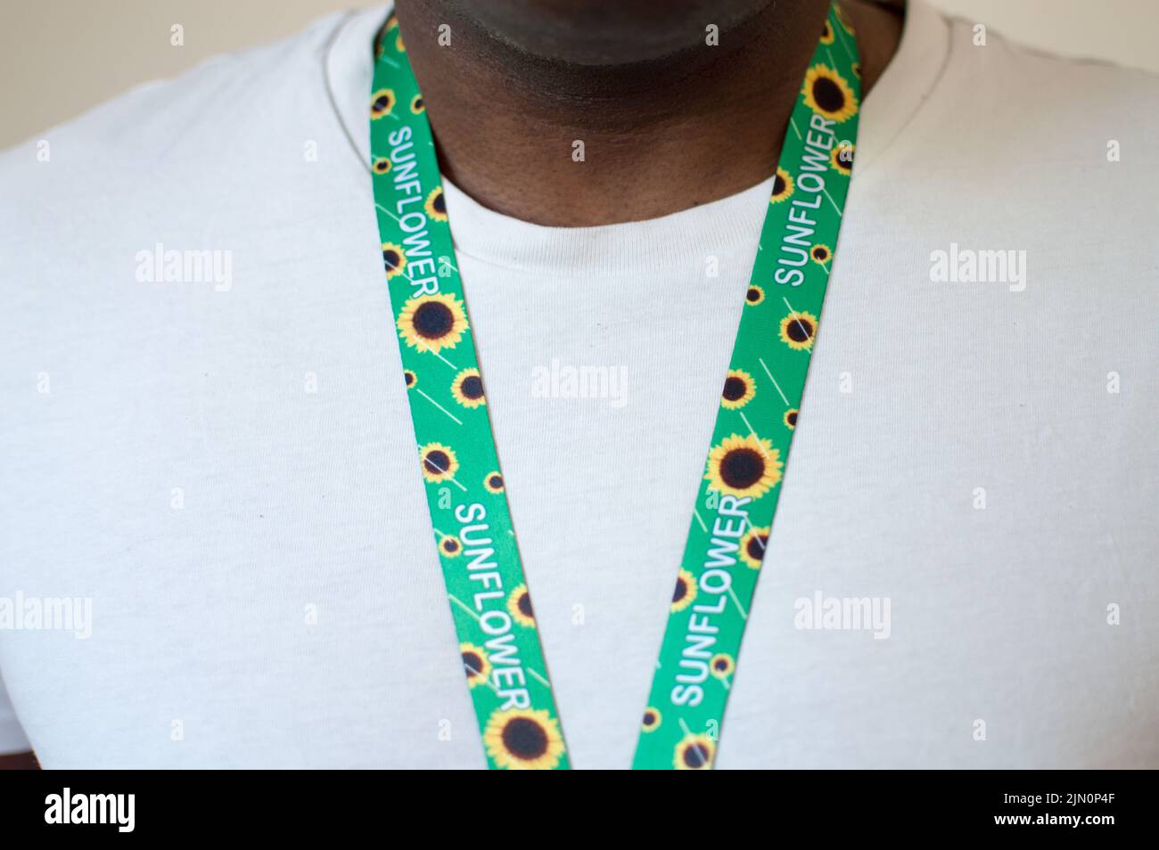 Front partial  view of a male adult wearing a sunflower lanyard indication of hidden disability Stock Photo
