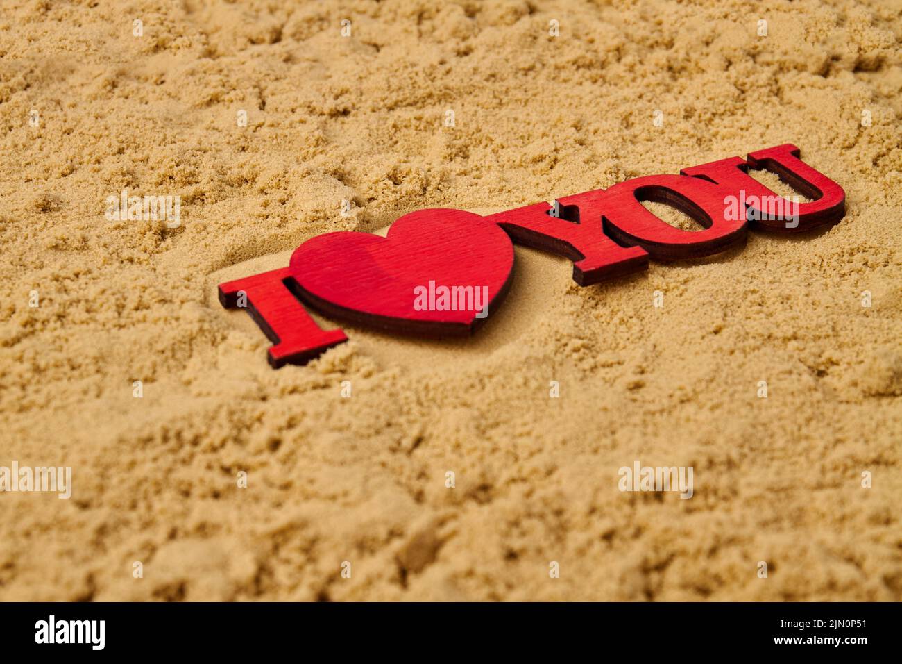 Close up red wooden I love you cutout on the sand. Honeymoon vacation concept. Stock Photo