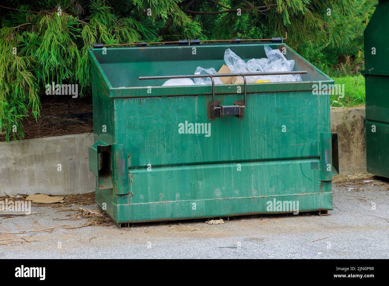 Located near an apartment building, there is a garbage container bin