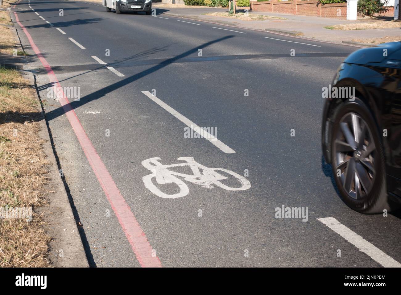 bicycle path painted on red route next to fast moving traffic Stock Photo