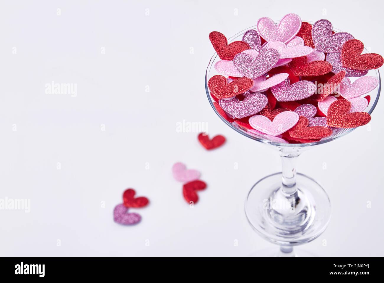 Close up cocktail glass filled with hearts. Valentines day concept. Isolated on white background. Stock Photo
