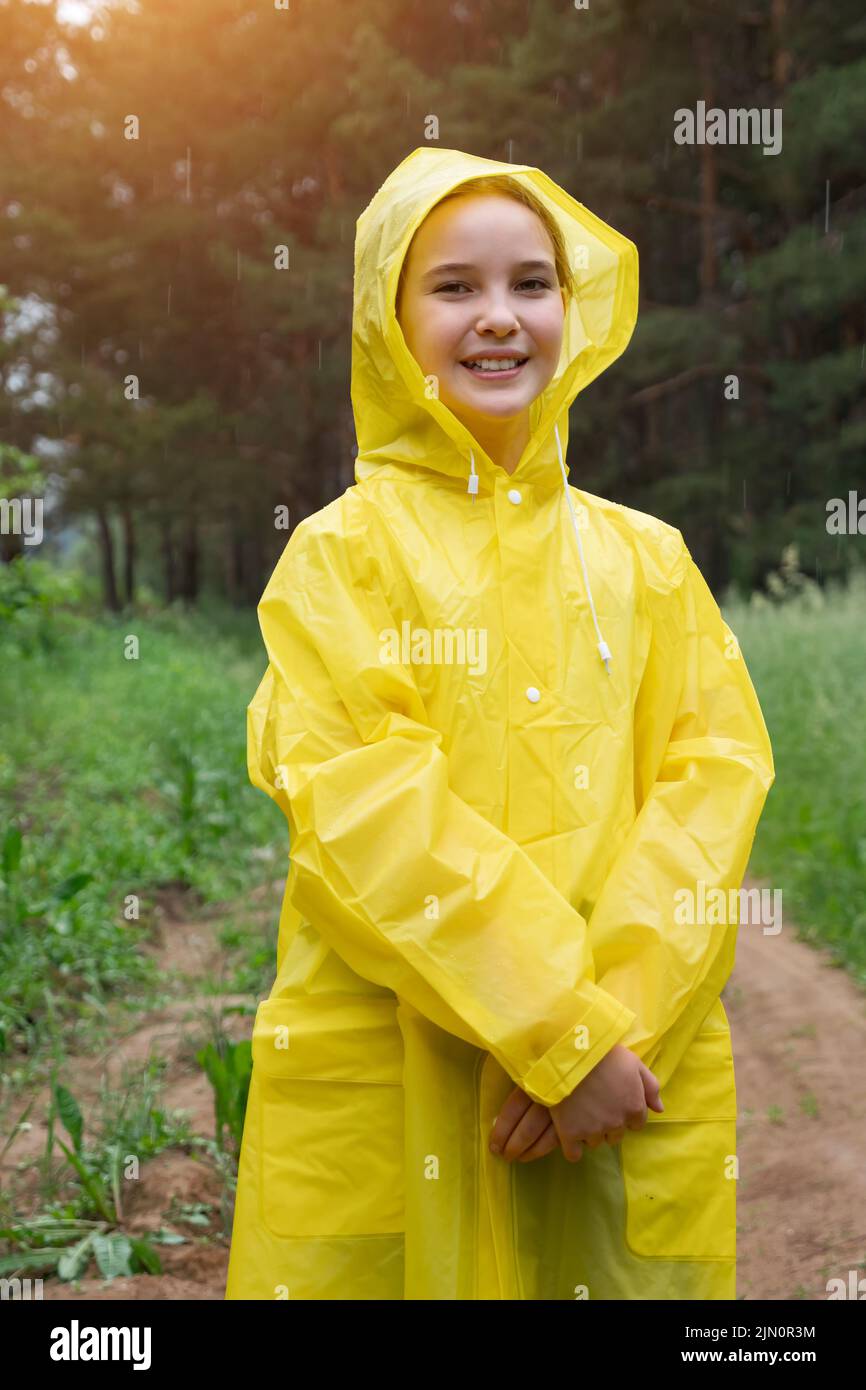 Happy girl in yellow raincoat walks enjoying summer nature Stock Photo