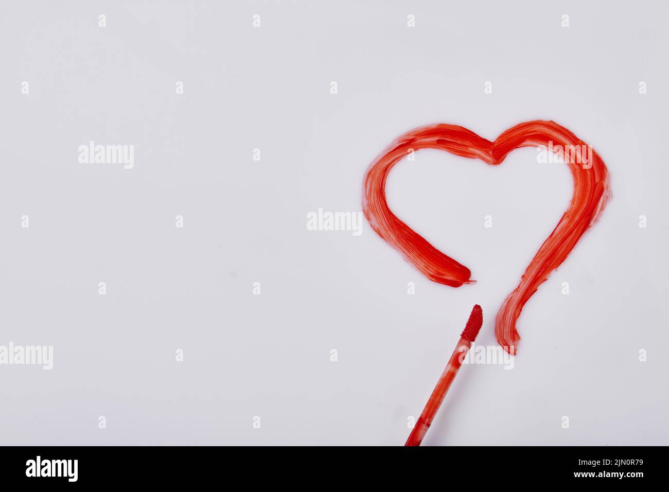 Red heart drawn by mascara on white surface. Valentines day concept. Stock Photo