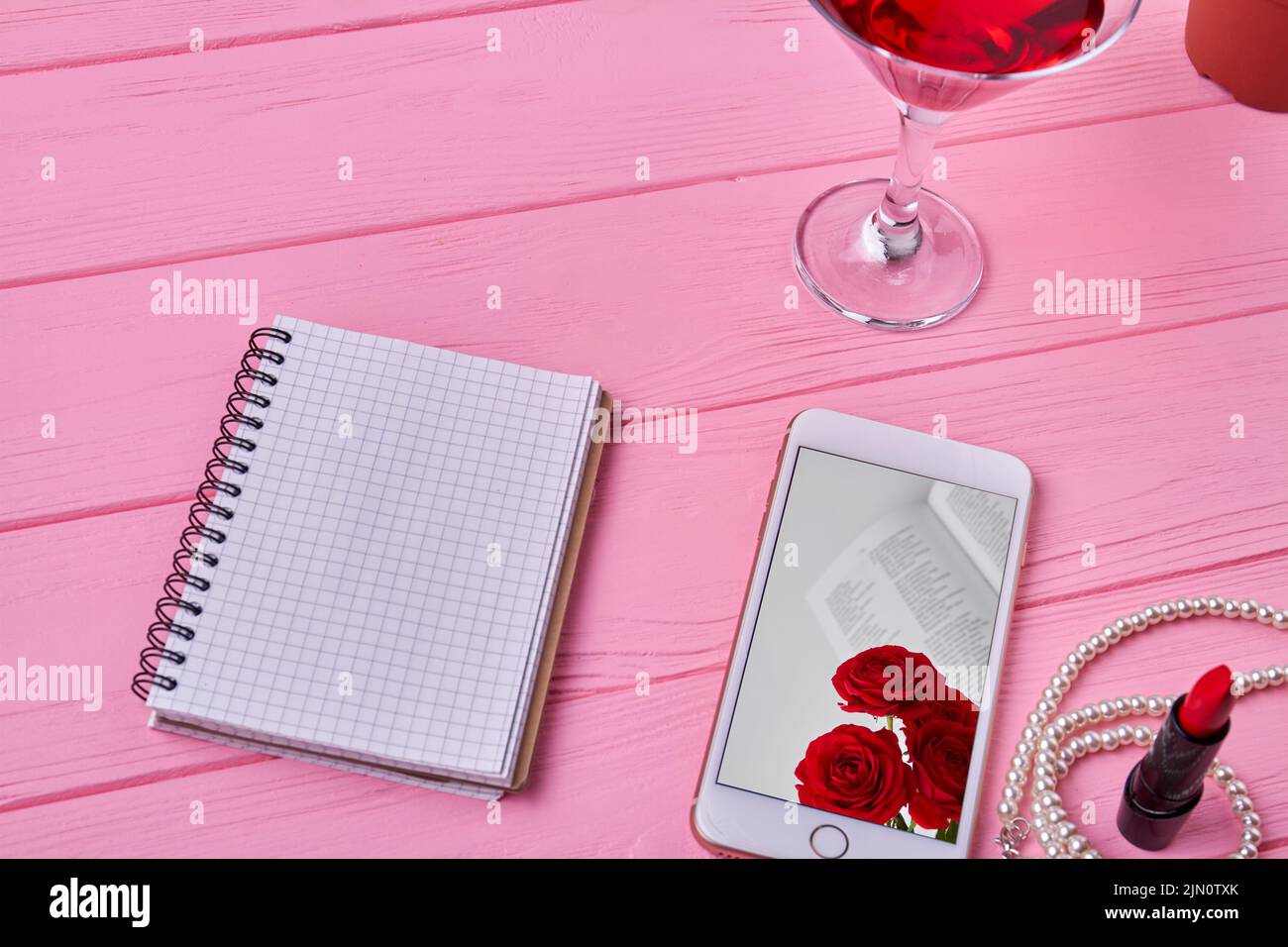 Top view open notepad with blank page and smartphone. Pink wooden desk. Stock Photo