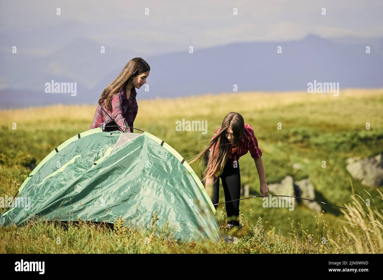 Hiking activity. Attach necessary structural components tent. Helpful to have partner for raising tent. Prepare for night. Girl scout concept. Women Stock Photo