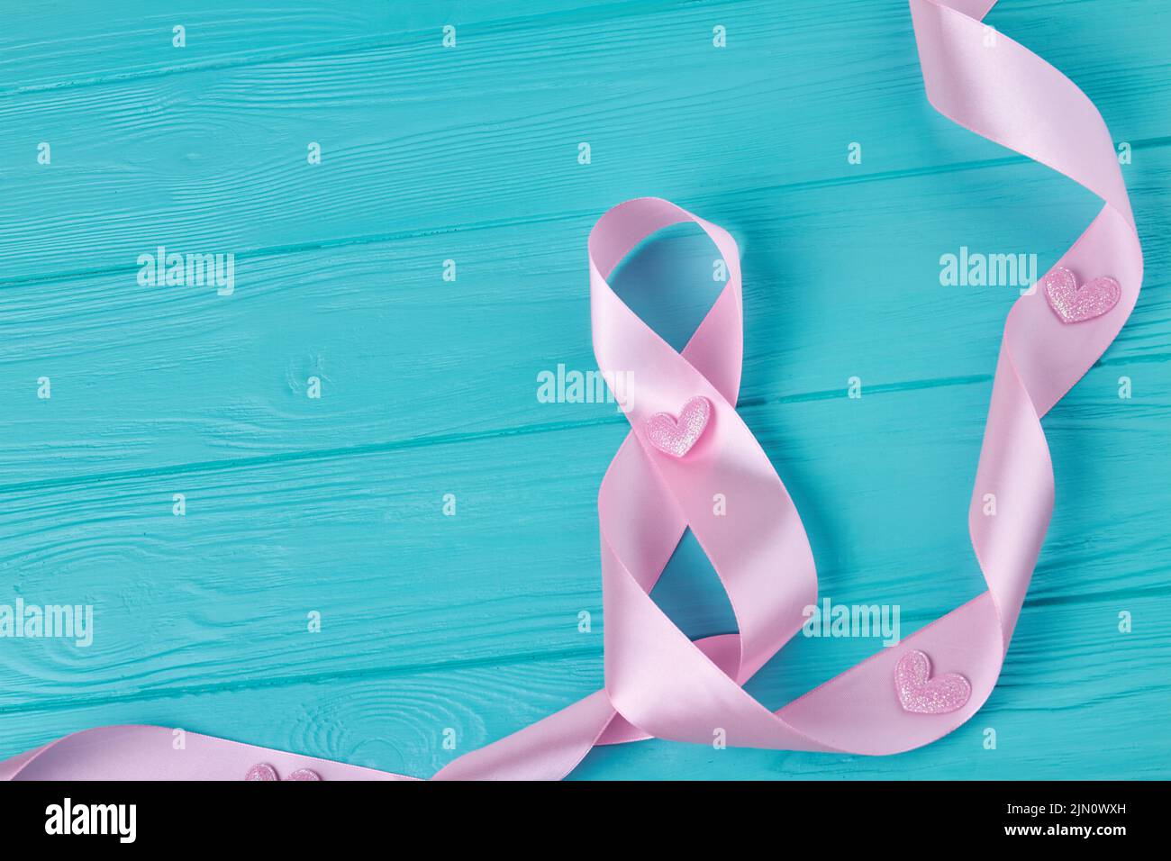 Pink ribbon tape on blue wooden desk. Happy women's day concept. Stock Photo