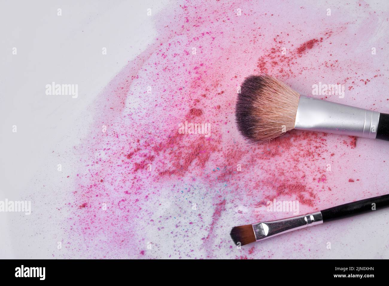 Makeup brush and scattered face powder on white background. Space for text. Stock Photo