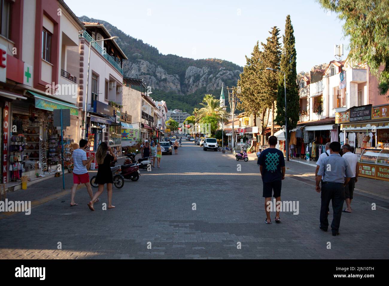Tourists walk past a cafeteria and souvenir store in small resort town. Street food and souvenir shops on main street. Turunc, Turkey - September 7, 2 Stock Photo