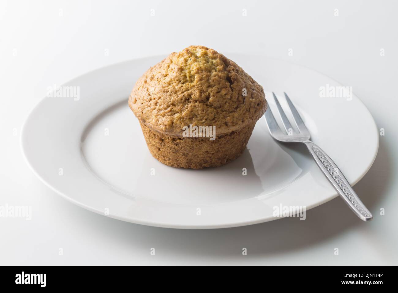 Muffin on white plate with cake fork Stock Photo