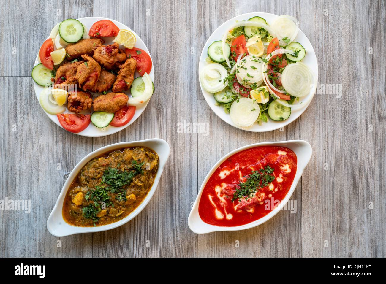 Doncaster, UK - 2019 Mar 21: Chicken tikka masala & chicken Bhuna, pakoras and green salad from Goa Indian Stock Photo